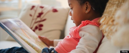 Black girl reading book on sofa